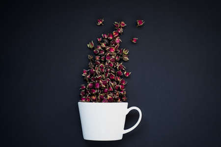 Blank white ceramic mug on black background with rosebuds exploding out of cupの写真素材