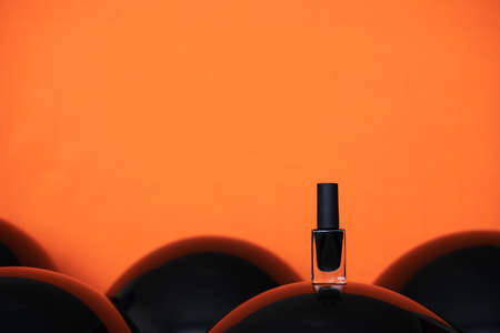 black nail polish on shiny balloon and orange background. copy space halloween banner mockup