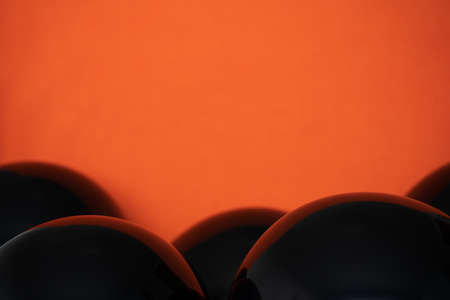 simple Close up shiny black balloons on orange background. Halloween spooky copy spaceの写真素材