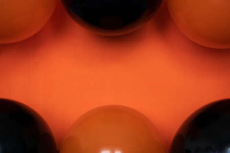 simple close up shiny black and orange balloons on orange background. Halloween spooky copy spaceの写真素材