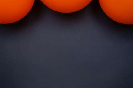 simple Close up shiny orange balloons on black background. Halloween spooky copy space