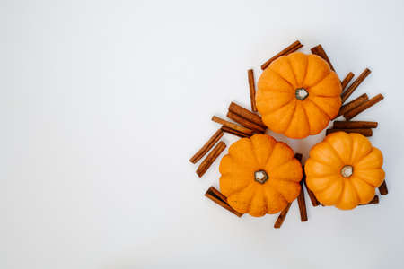three small orange pumpkins with cinnamon sticks top view flat lay. Halloween and Thanksgiving autumn conceptの写真素材