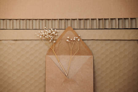 textured recycled cardboard background pattern with brown paper envelope and baby's breath...