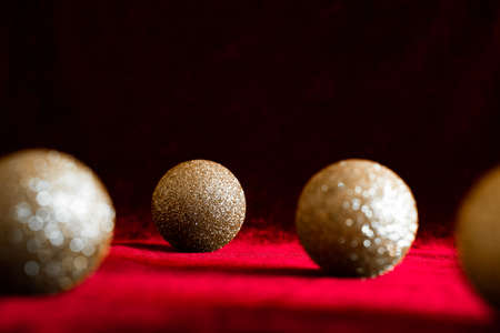 Gold glitter christmas balls on red velvet background with low key dark moody lighting background. Classic holiday colors, luxury festive atmosphereの写真素材