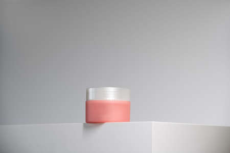 soft pink cream pot with silver lid on white podium and background. Modern geometric minimalism in self-care beauty. Hero shotの写真素材