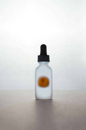 dark backlit face serum white matte glass bottle with dropper with orange. Anti aging facial liquid with vitamin C. Organic bio cosmeticsの写真素材
