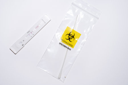 Positive at-home covid self-test with swab in biohazard plastic bag on white background. Over-the-counter OTC tests for corona pandemicの写真素材