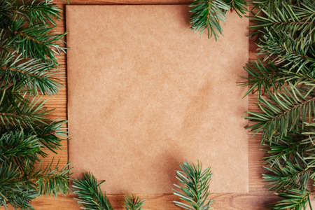 dark green lush pine fir branch frame on light brown wood and recycled brown paper background fir...