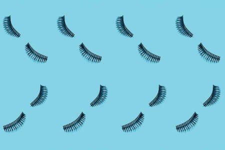 Black fluffy eye lash pattern on blue background. Holiday beach season and beauty. Modern trendy simple minimalistic shotの写真素材