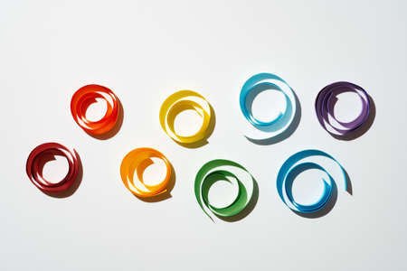 Rainbow colored paper circles on white background. Multicolor spirals pride