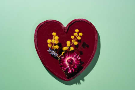 Red wax heart on green background with dried flowers. Lavender, mimosa and helichrysum bracteatum strawflowerの写真素材
