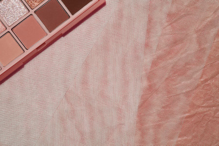 Top view eyeshadow rose gold glitter and beige mauve and brown matte palette on beige background....