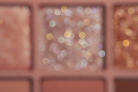 Blurred nude eyeshadow palette with glitter texture background. Cosmetic banner with beautiful bokeh