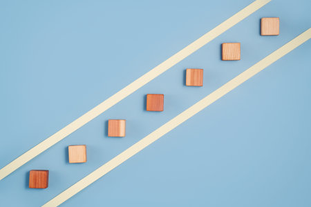 blank wooden cubes in a diagonal line shades ranging from dark to light beige on blue background....