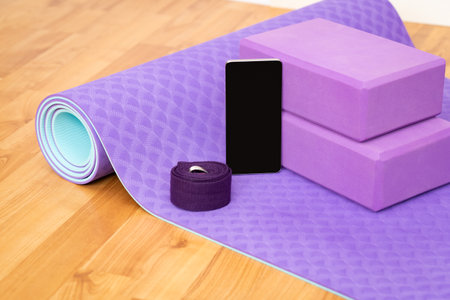 Blank phone on purple yoga mat with blocks and strap. Health app and home sport self-care conceptの写真素材