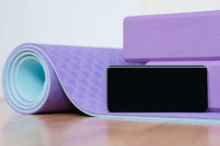 Blank horizontal phone on purple yoga mat with blocks. Health app and home sport self-care concept