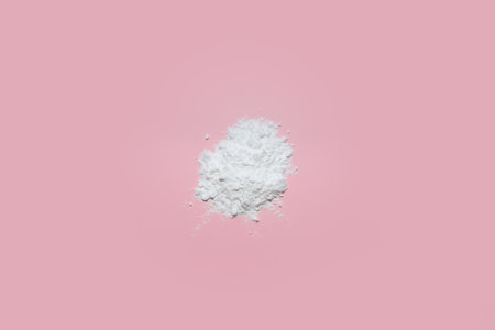 A minimalist and elegant composition featuring a pristine white face powder delicately arranged on a...