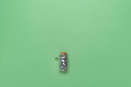 Glass phial with silver stars and lucky clover shamrock pendant. St Patrick's holiday background for...