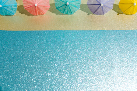 Abstract beach with glitter paper sand and water and cocktail umbrellas. Summer aesthetic mockup...