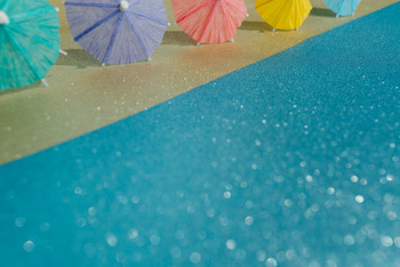 Abstract beach with glitter paper sand and water and cocktail umbrellas. Summer aesthetic mockup...