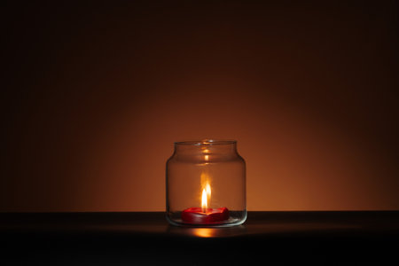 red candle in glass on orange Halloween background. Spooky minimalist bannerの写真素材
