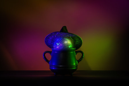 Creative minimalist Halloween image featuring a witch hat on a cauldron with a glowing disco ball. Perfect for modern and trendy Halloween designs.の写真素材