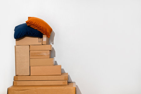 Creative minimalist image of stacked cardboard boxes and pillows on a plain background, representing...