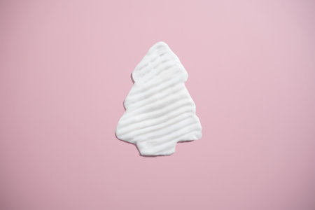 white cream shaped like a Christmas tree on pink background.の写真素材
