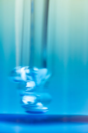 Smudgy close-up photo of a dropper with air bubbles inside a blue glass bottle. Concept of cosmetic, skincare, serum, product detail, texture, realism, imperfection, beauty photography.の写真素材