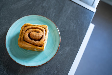 Classic roll on an artisan ceramic plate in a home kitchen, top view. Warm tones and natural light...