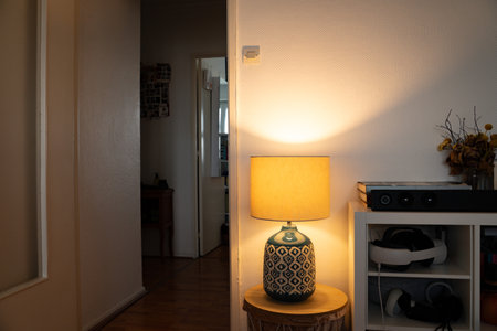 Table lamp placed on a small table in a cluttered living room. Everyday home interior scene showing...