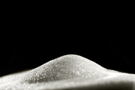 Sparkly hourglass sand on black background. Minimalist low key photo for concepts of time, travel to the desertの写真素材