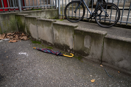 Closed umbrella lying next to a concrete wall near bike parking in an urban outdoor setting....