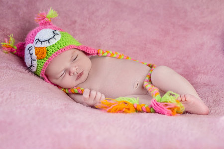 Newborn baby in a knitted hat on a pink backgroundの写真素材