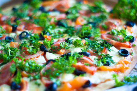 Aromatic pizza with mozzarella cheese, tomatoes, olives, pepper and greensの写真素材