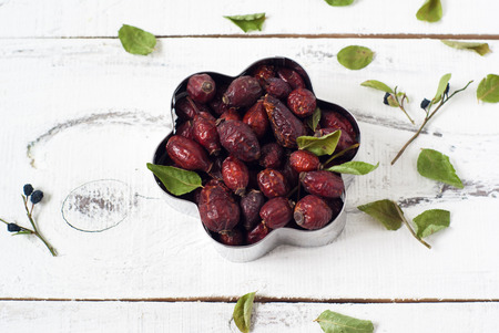 rosehips in tins of cookies on the white table dervyannomの写真素材