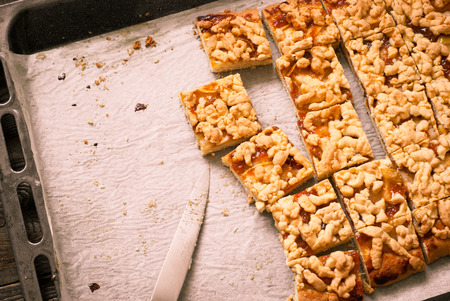 Pie with apples and apricot jam cut into pieces on a baking. Image tintingの写真素材