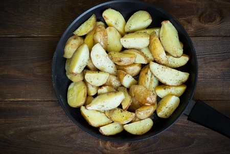 Frying pan with slices Baked potatoes with herbs and pepperの写真素材