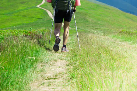 Hiking in the mountains. Hiker goes on the trail in the mountains