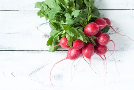 Radishes with green leaves at white wooden tableの写真素材