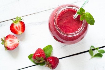 Strawberry smoothie in a glass jar with green ribbon at the white table. Top viewの写真素材