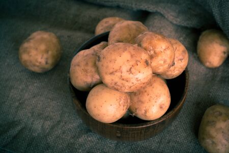 Raw potatoes in a wooden bowl on sackingの写真素材
