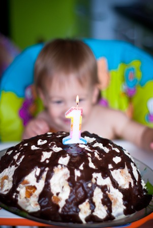 Baby boy blows out candles on a cake on his first birthdayの写真素材