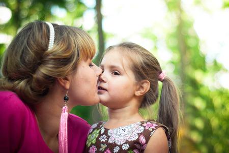 Mother and daughter together in the park kiss each otherの写真素材