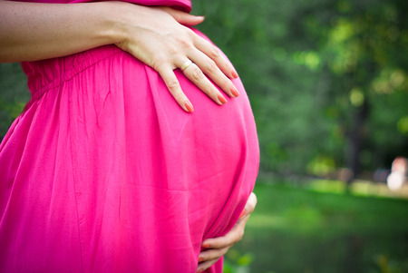 Pregnant woman in a pink dress outdoorsの写真素材