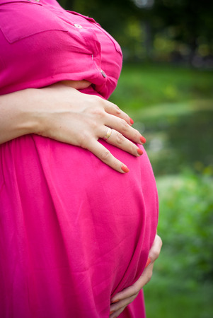 Pregnant woman in a pink dress outdoorsの写真素材