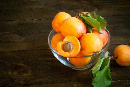 Some ripe apricots in a glass bowl on a wooden table Selective fokus.の写真素材