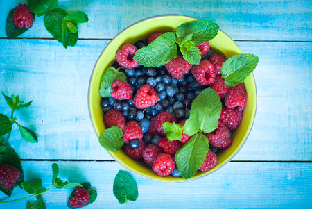 Blueberries and strawberries with mint leaves in the bawlの写真素材