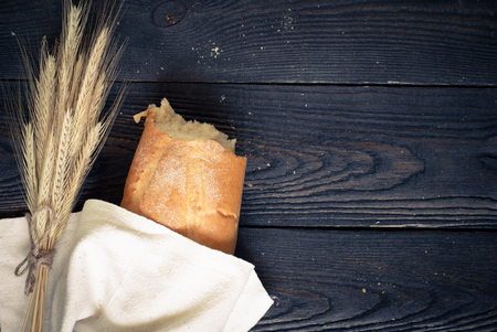 White baguette or French bread with wheat on the wooden table. Rustic Style. Image toned, copy space.の写真素材