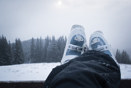 Legs skier in ski boots while relaxing after a day skiing. Mountain scenery awayの写真素材